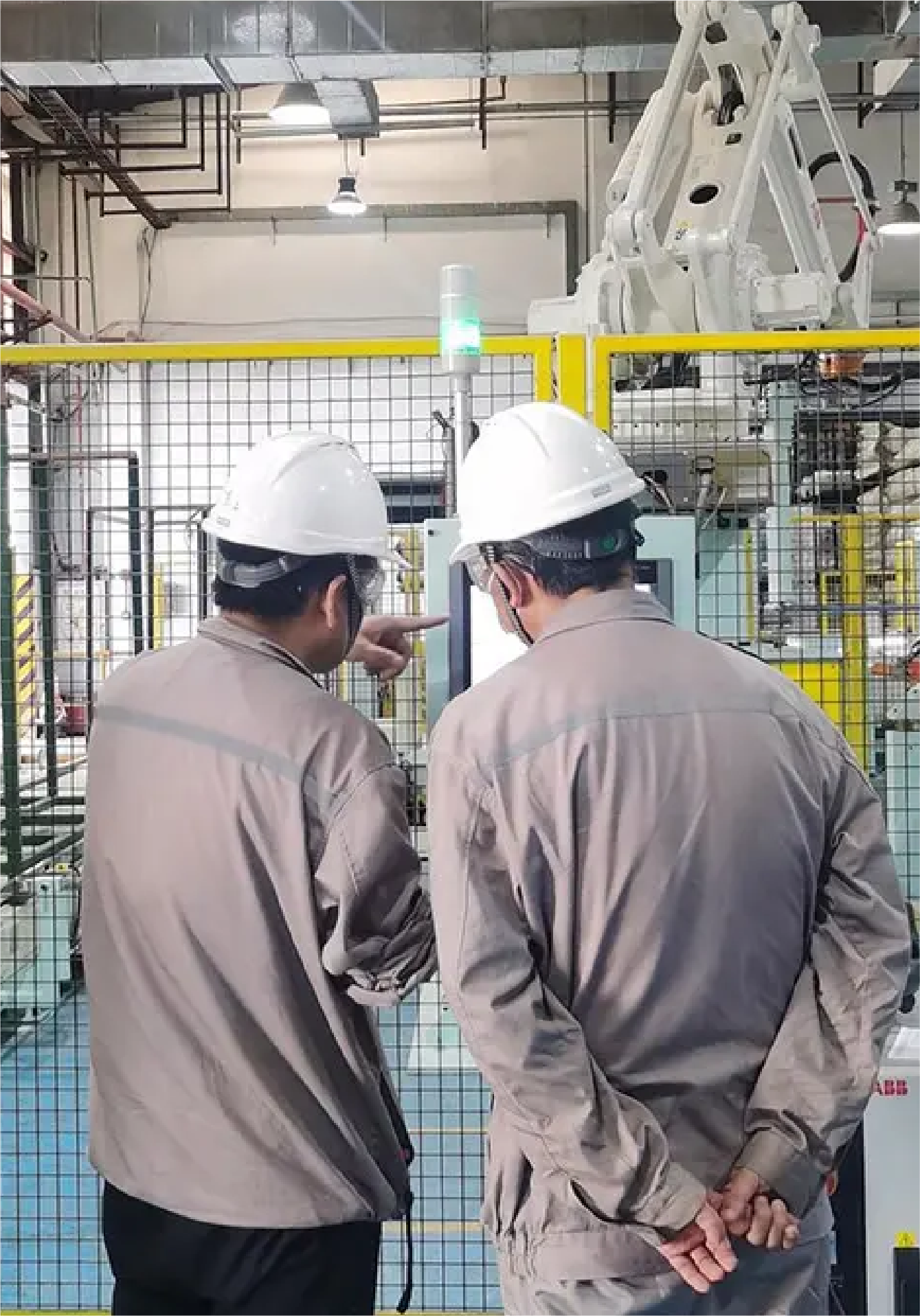 Two workers in safety gear examining equipment inside an industrial manufacturing facility.